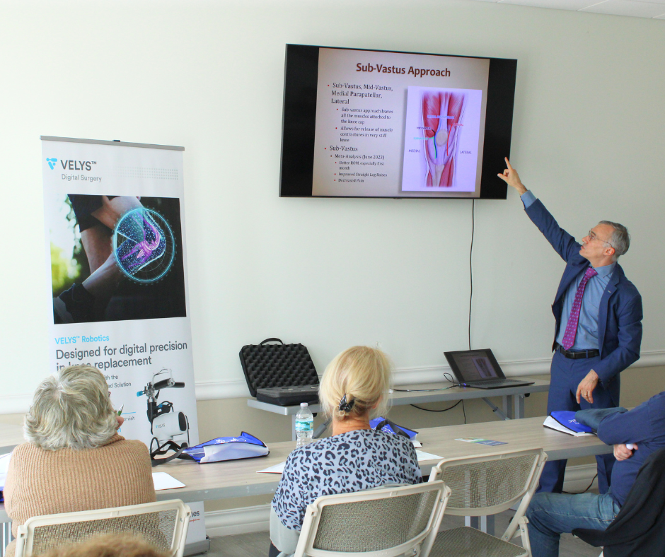 Dr. Hatten presenting the subvastus approach to patients alongside a VELYS Digital Surgery display